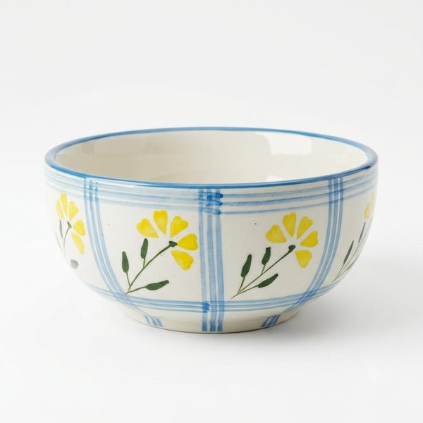 A white ceramic bowl decorated with a blue grid pattern and yellow flowers with green stems, shown on a clean white background.