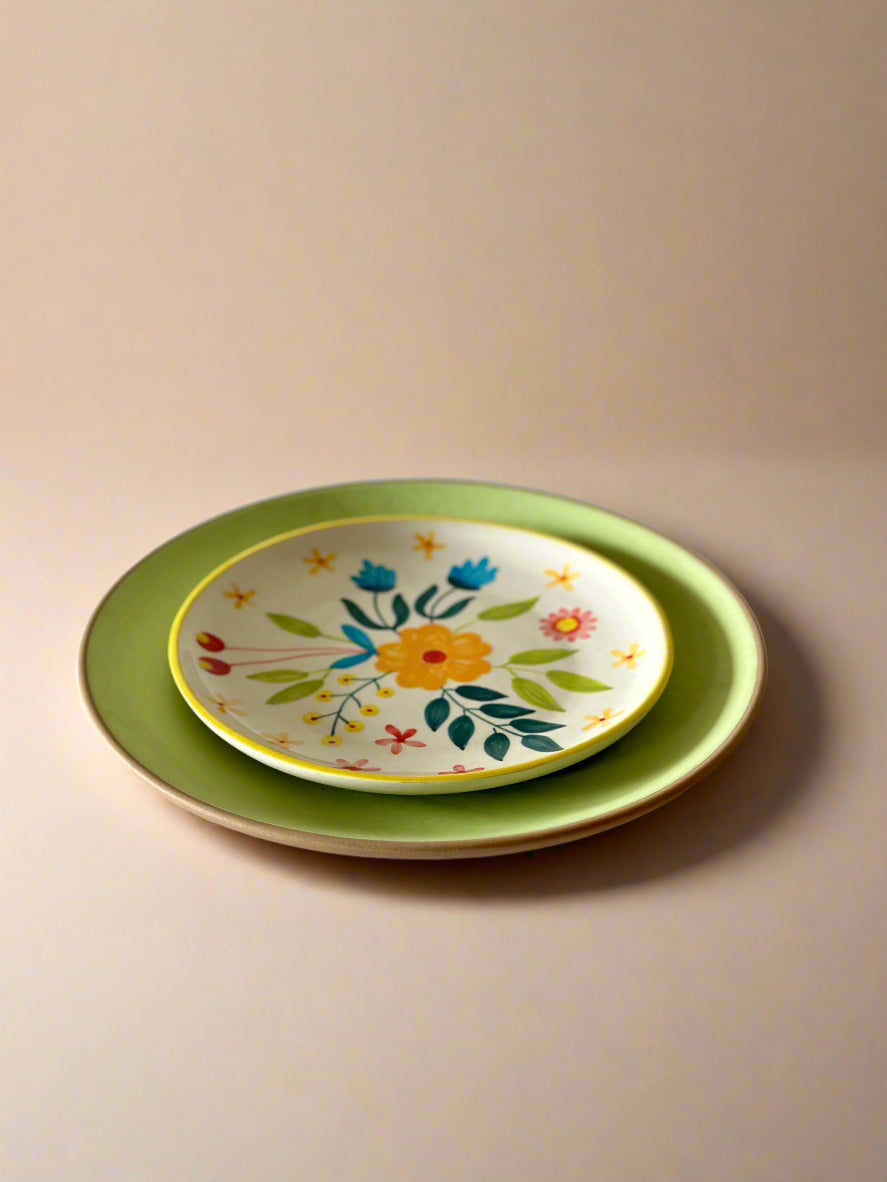 Two ceramic plates, one with floral design, on a light surface.