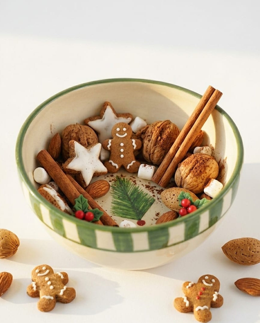 Decorative bowl with gingerbread cookies, cinnamon sticks, and nuts on a white background