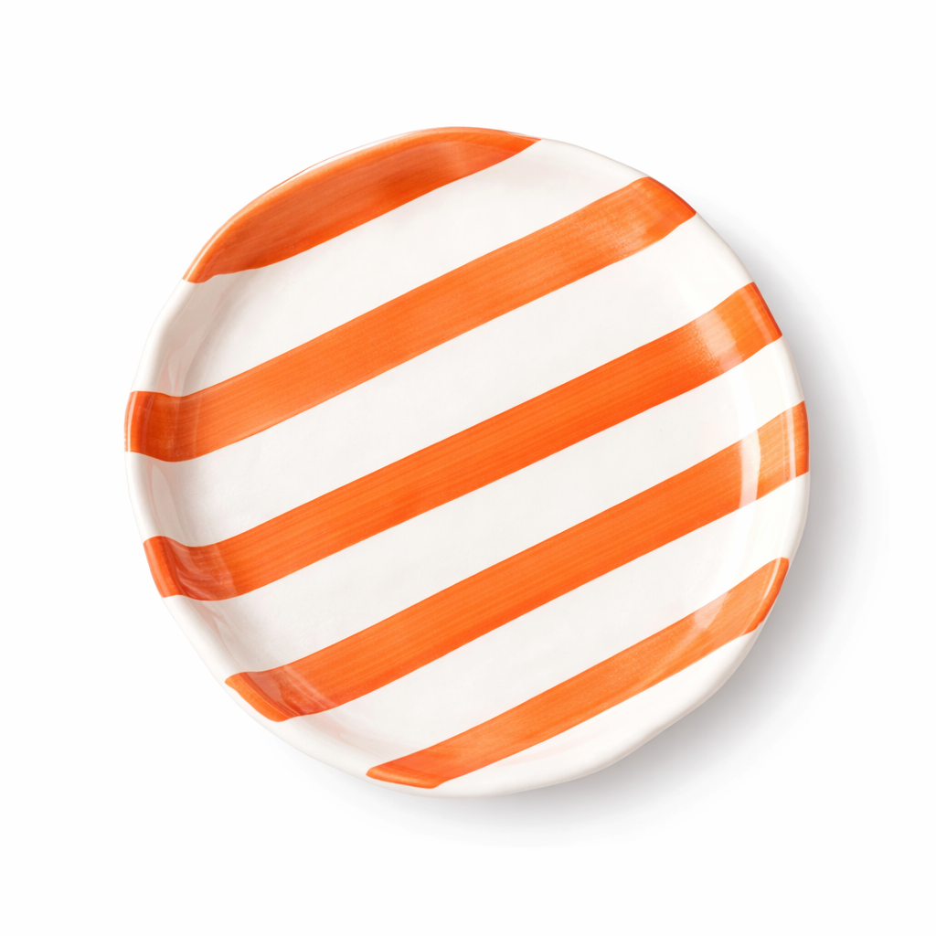 Round plate with orange and white stripes on a white background