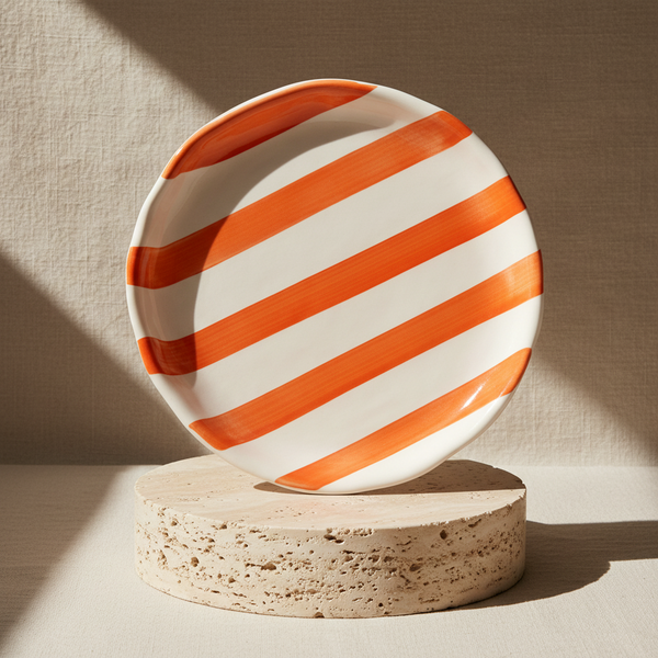 Round plate with orange and white stripes on a white background