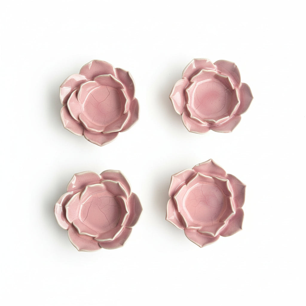 Four pink ceramic flower-shaped dishes on a beige background