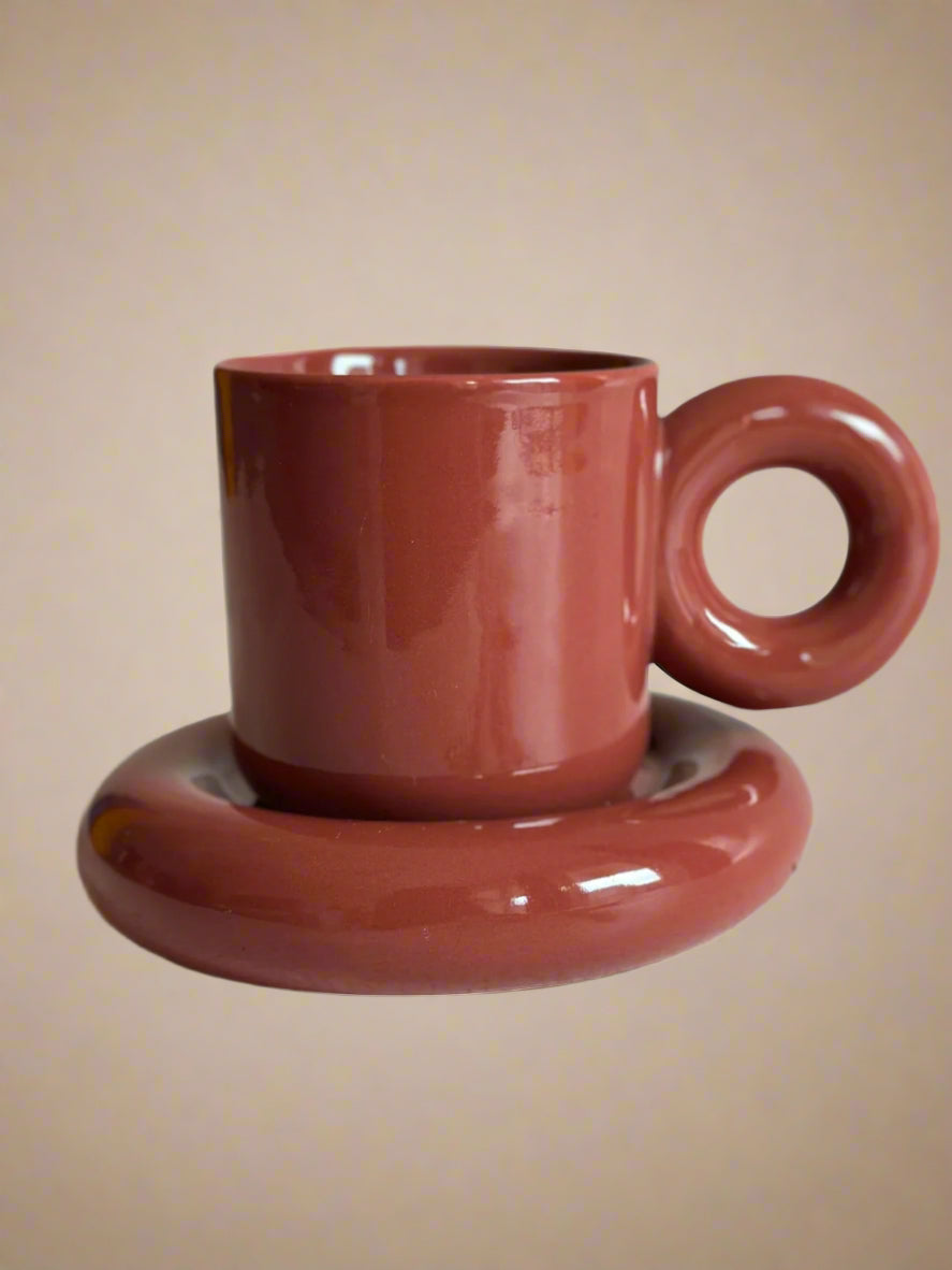 a red coffee cup sitting on top of a saucer