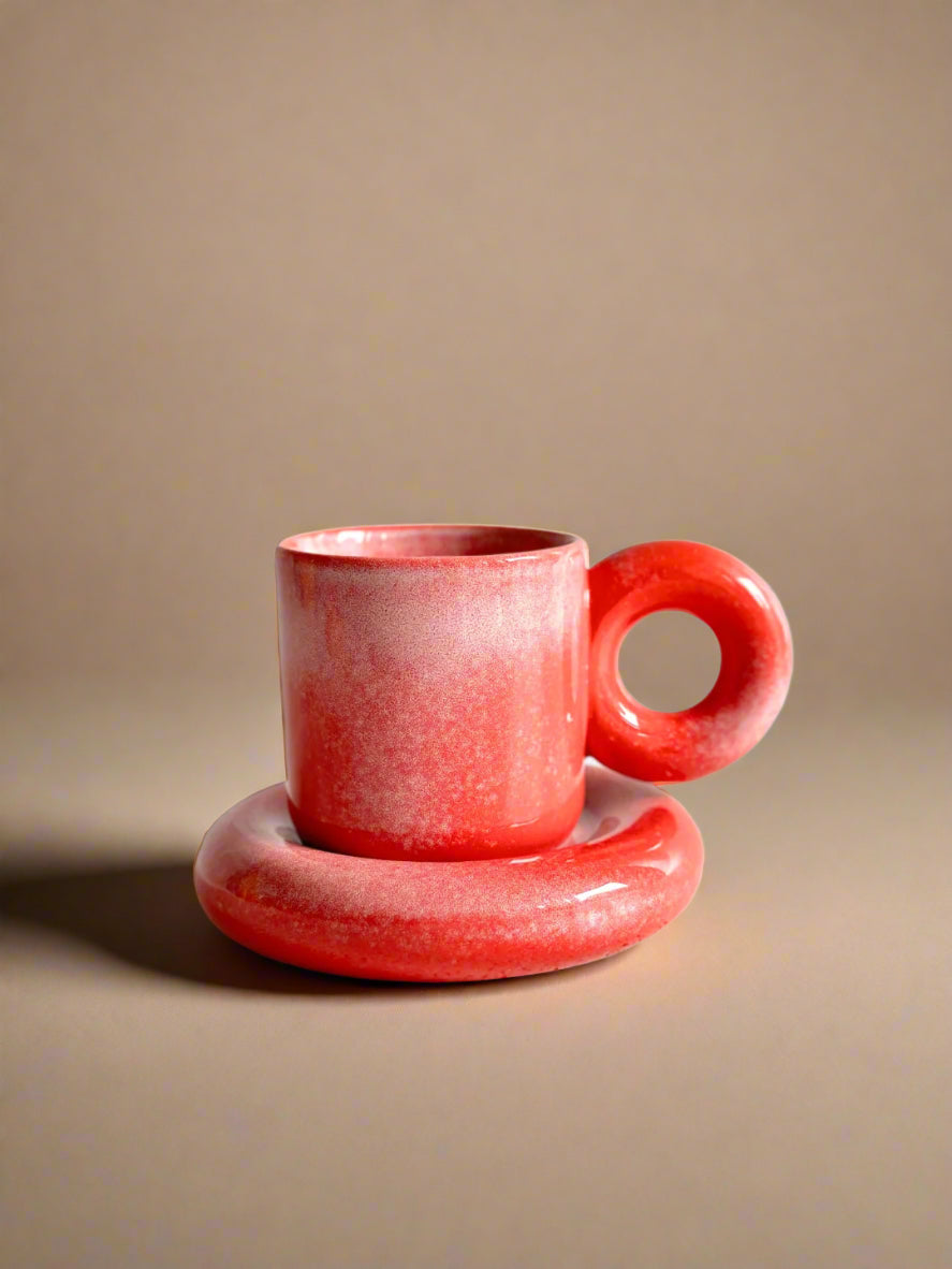 a red cup sitting on top of a saucer