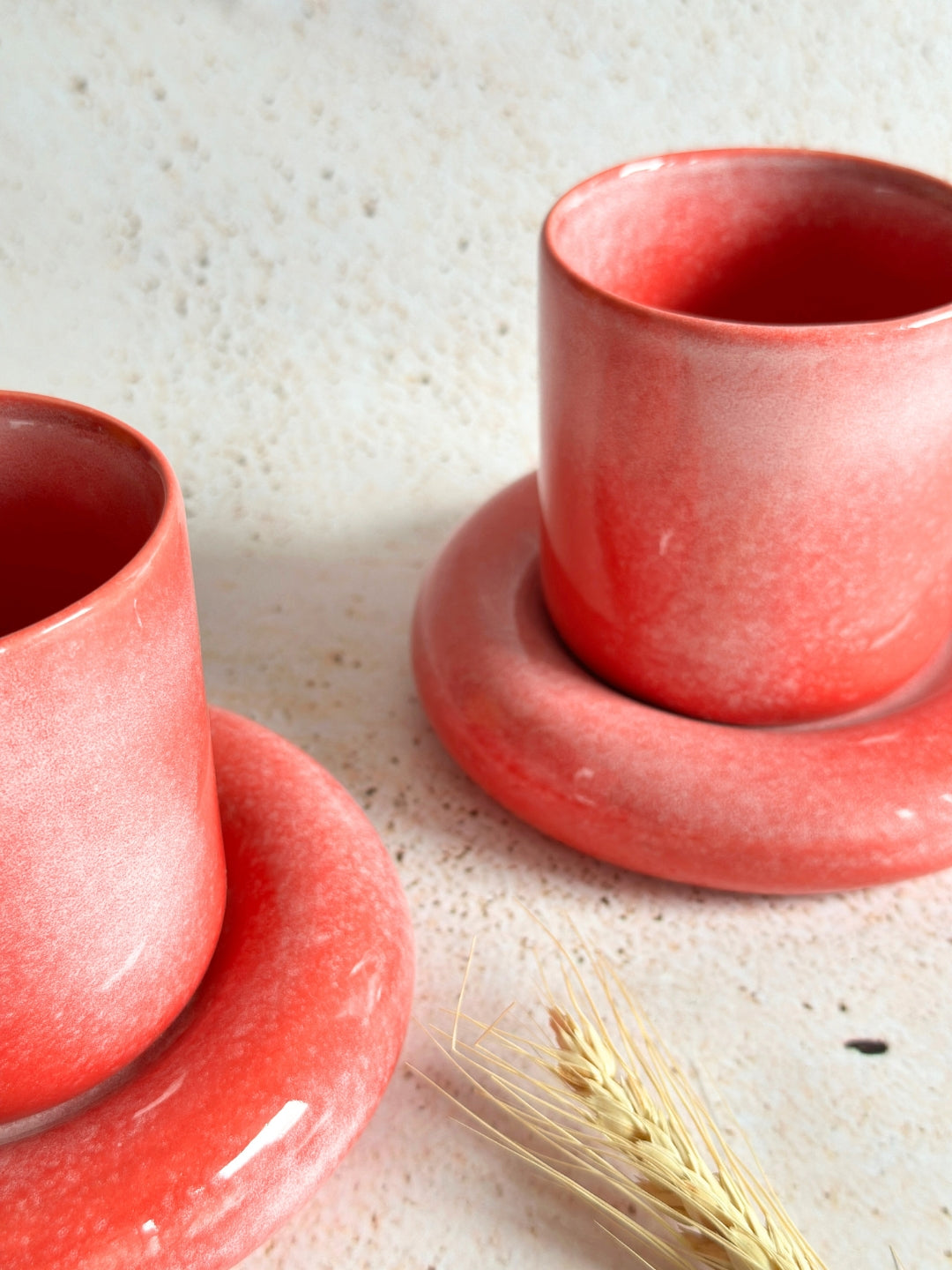 a couple of red cups and saucers on a table