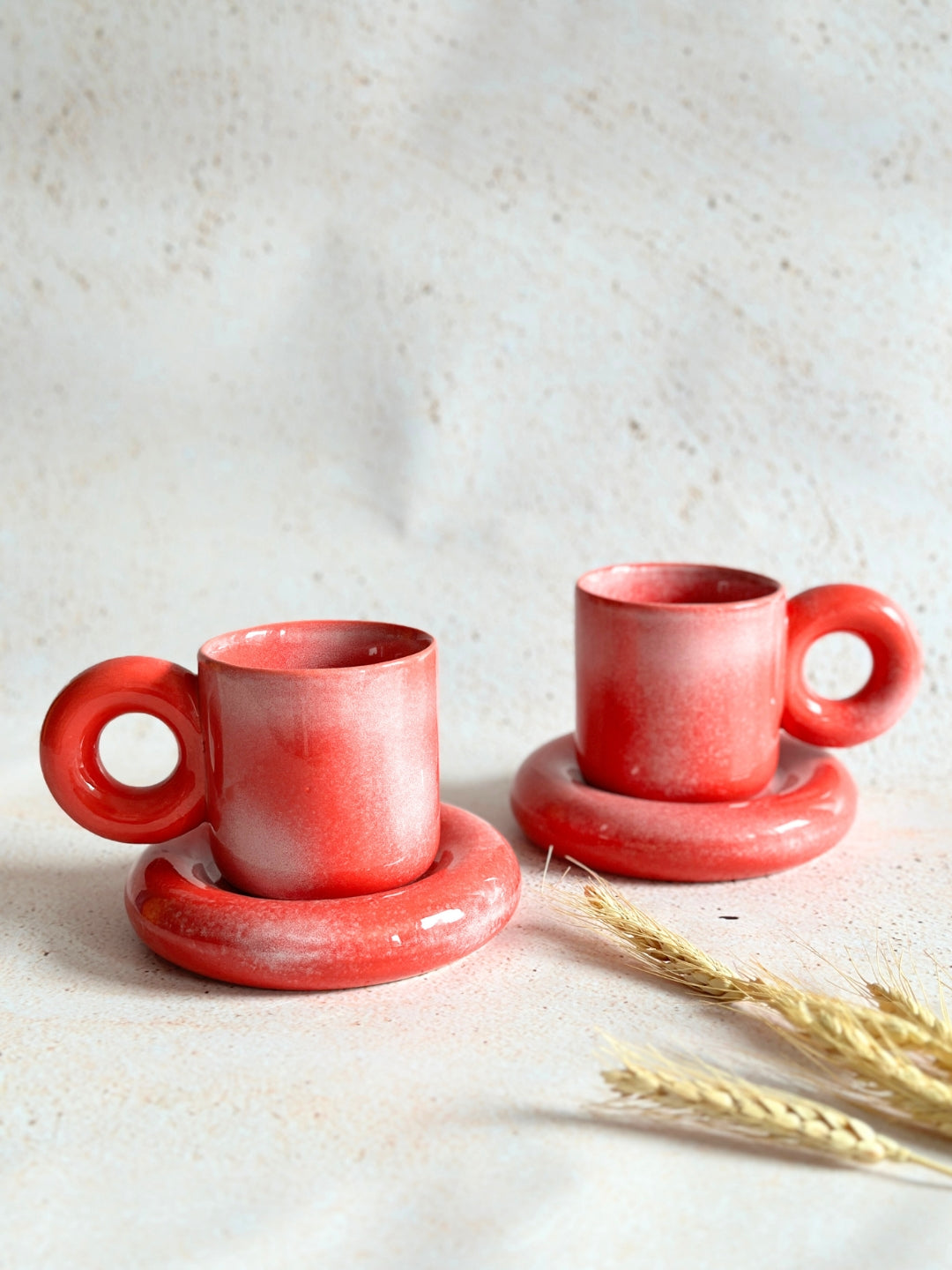 a couple of red cups and saucers sitting on top of a table