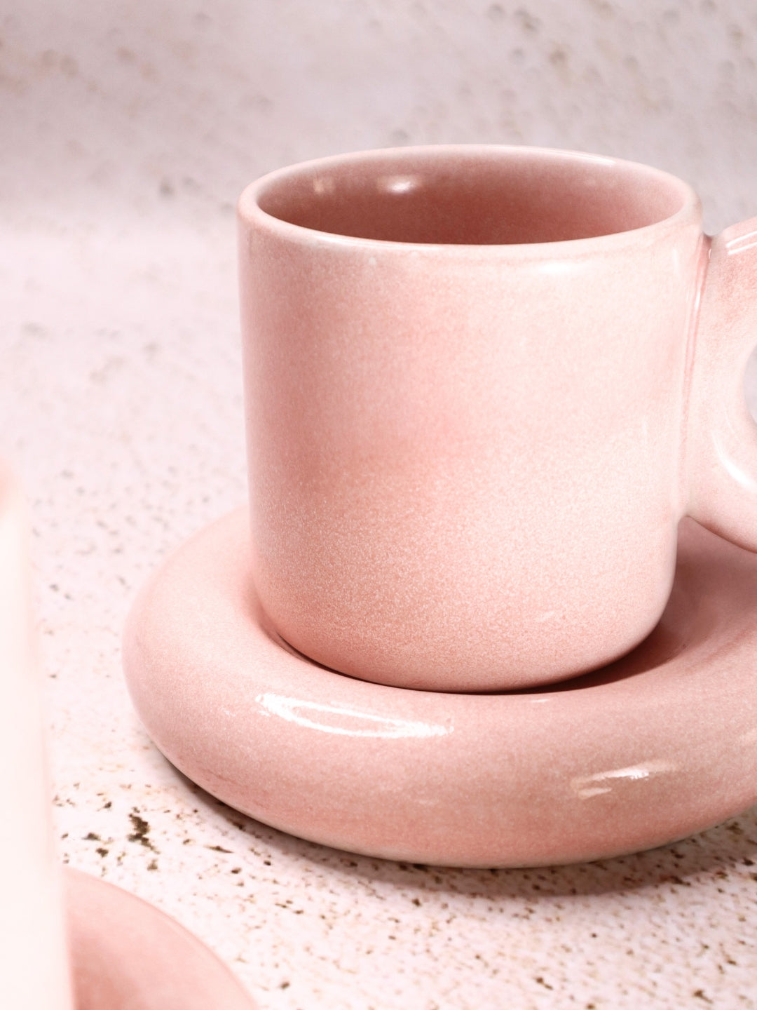 a pink cup and saucer sitting on a table