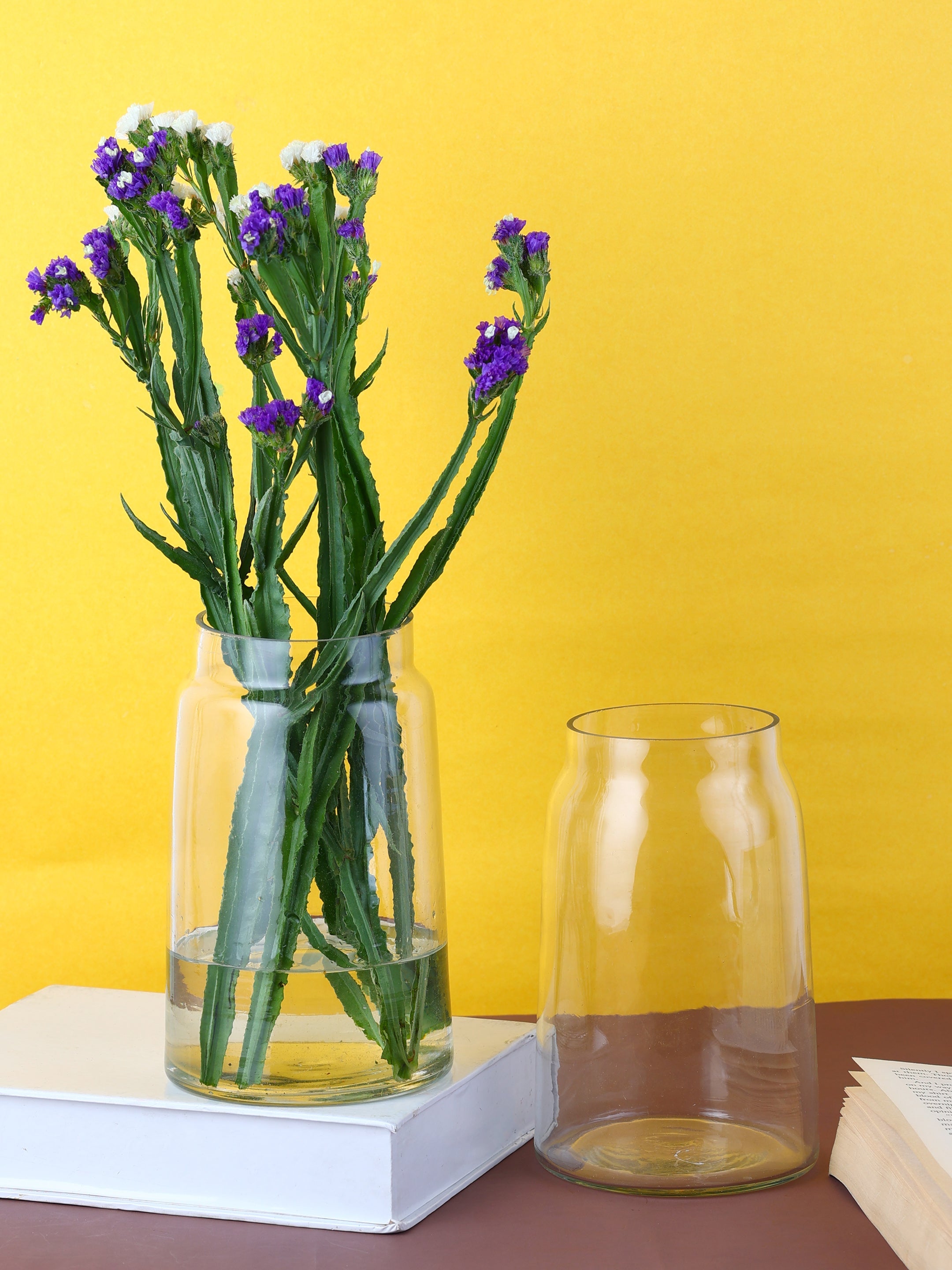 a vase with purple flowers sitting next to a book