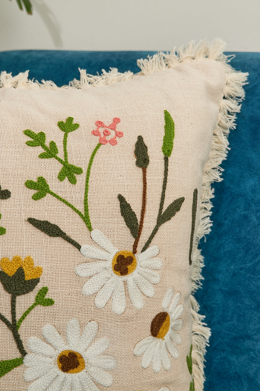 a blue chair with a white pillow with flowers on it