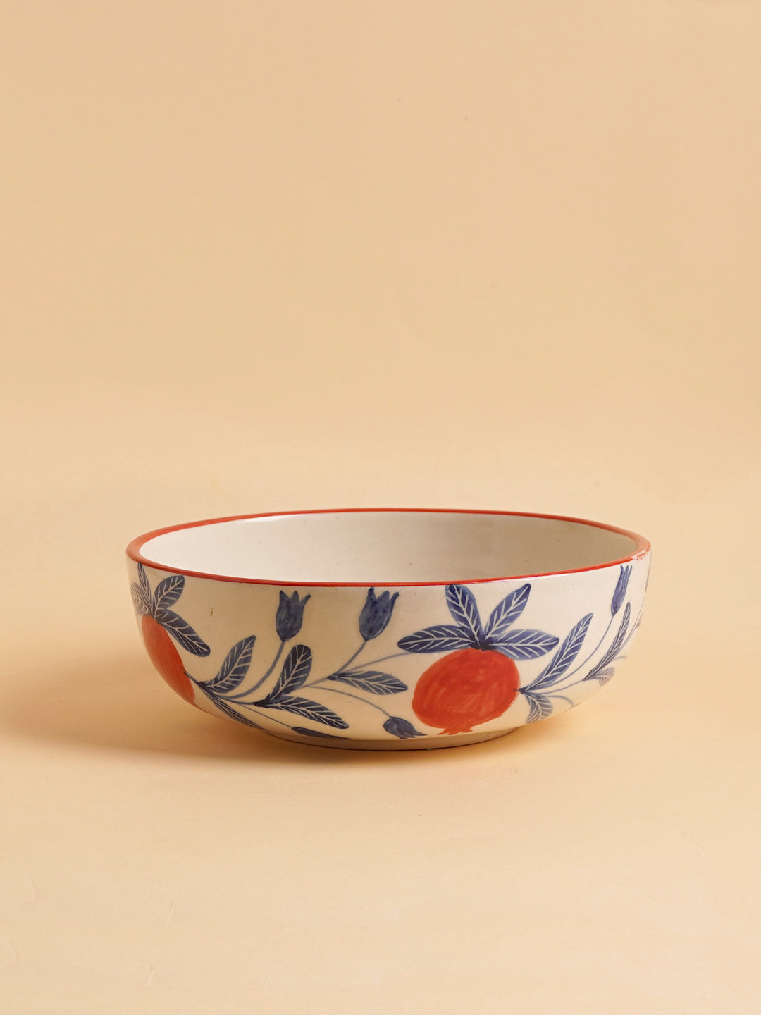 A large ceramic serving bowl with a red rim and blue floral patterns on a beige background.