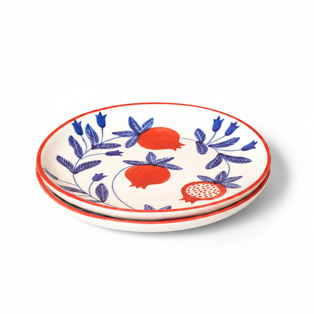 Stack of ceramic plates with blue floral and red fruit design on a beige background