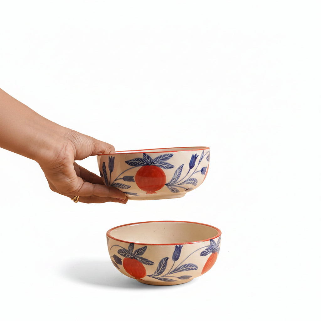 Hand holding a small ceramic bowl with floral patterns, another bowl is placed on a surface.