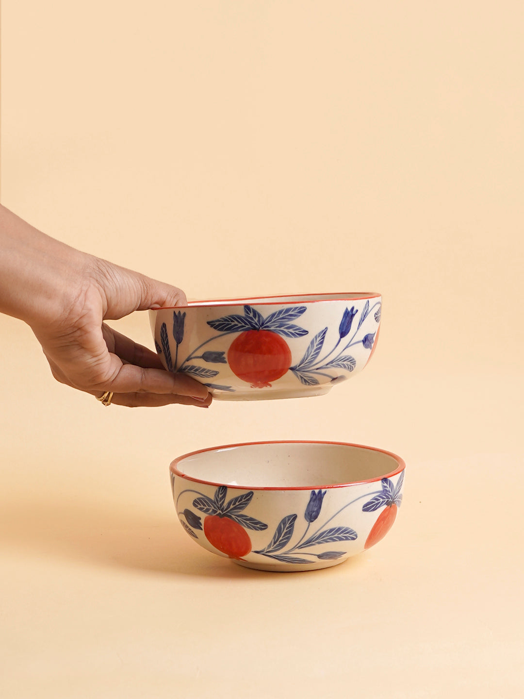 Hand holding a small ceramic bowl with floral patterns, another bowl is placed on a surface.