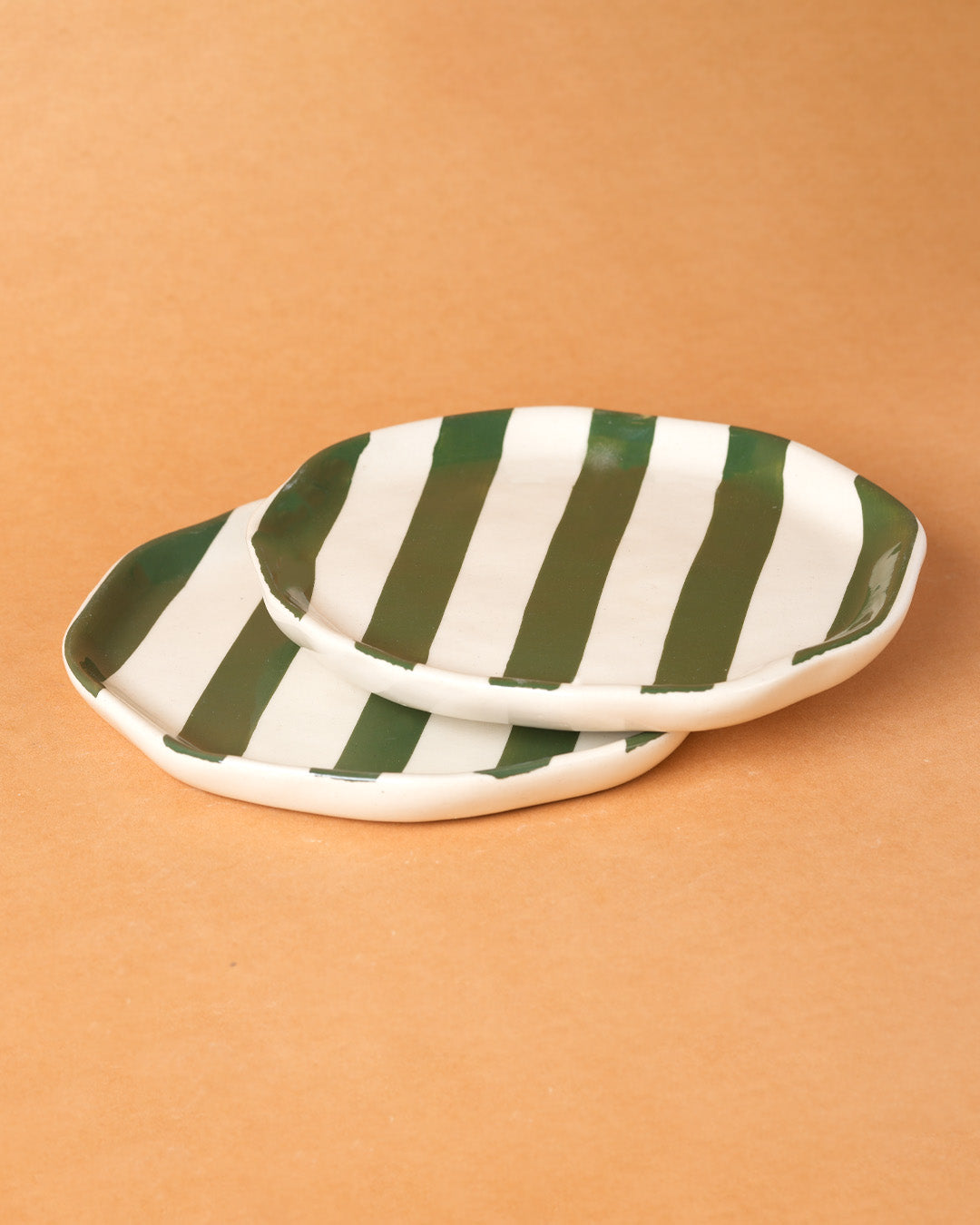Green and white striped ceramic dish on a beige background
