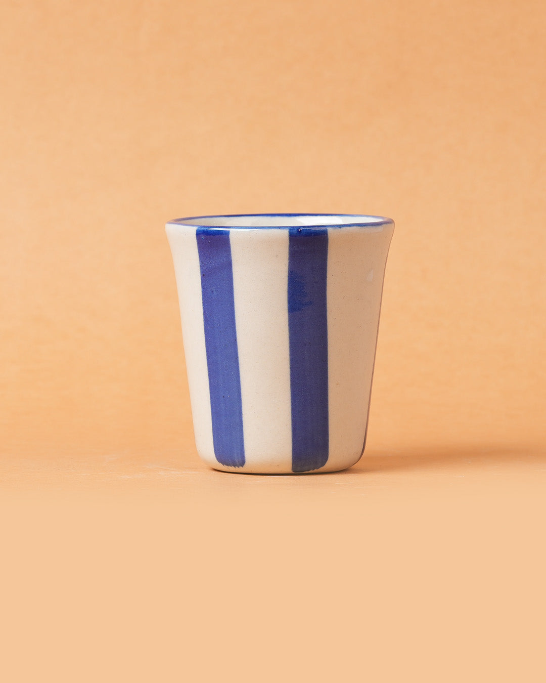 Ceramic cup with blue stripes on a beige background