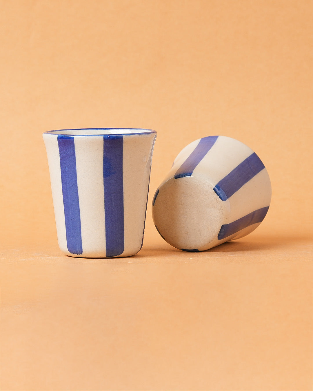Ceramic cup and ball with blue stripes on a beige background