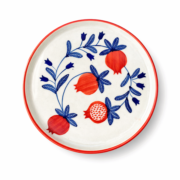 Decorative plate with red pomegranate and blue leaves design on a white background