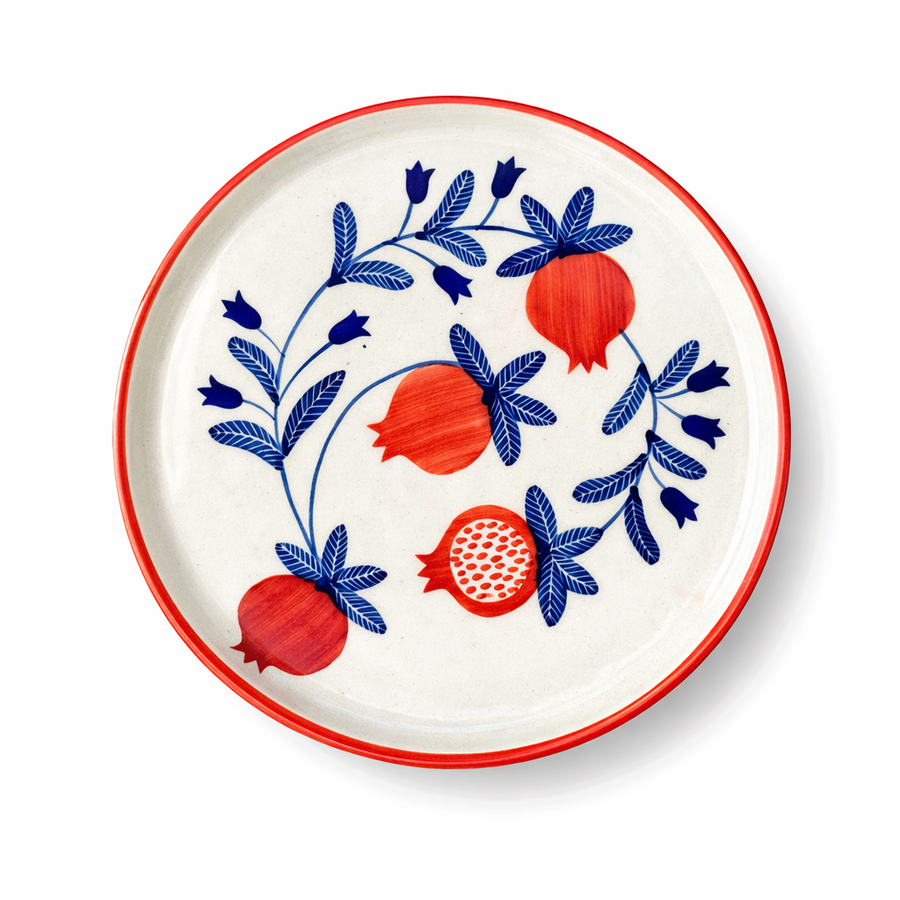 Decorative plate with red pomegranate and blue leaves design on a white background