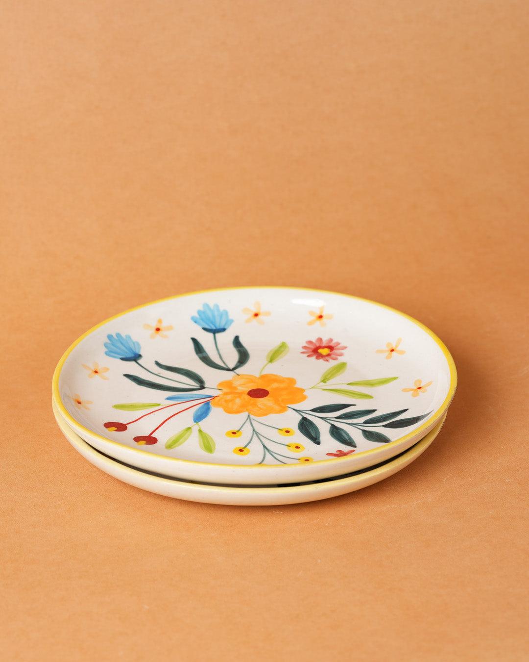 Two ceramic plates with floral designs on a beige background