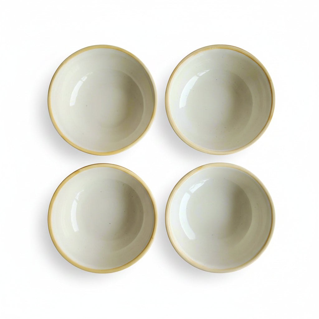 Four ceramic bowls with gold rims on a white background