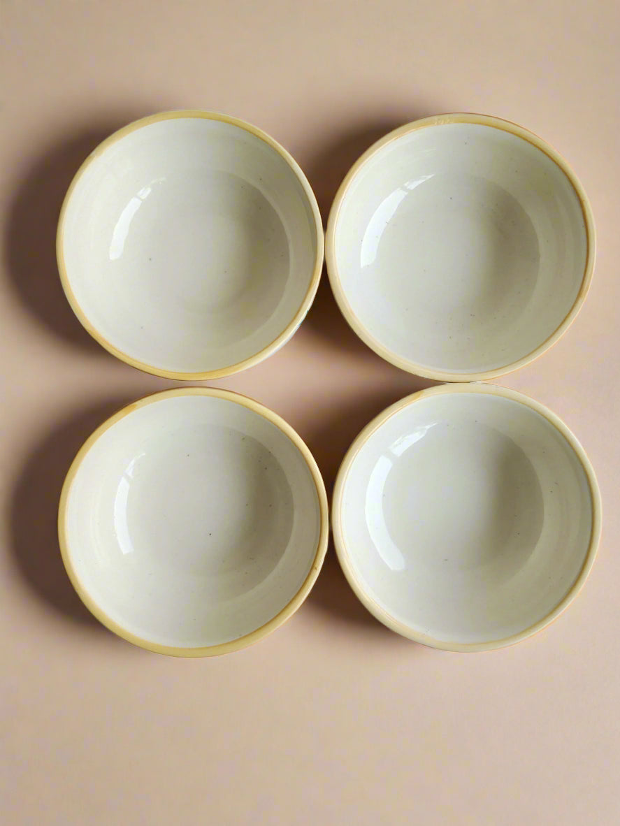 Four ceramic bowls with gold rims on a white background