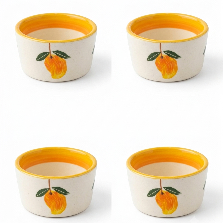 Four small ceramic cups arranged in a 2x2 grid on a white background. Each cup has an off-white exterior decorated with a yellow-orange fruit and green leaves, and a bright yellow-orange interior.