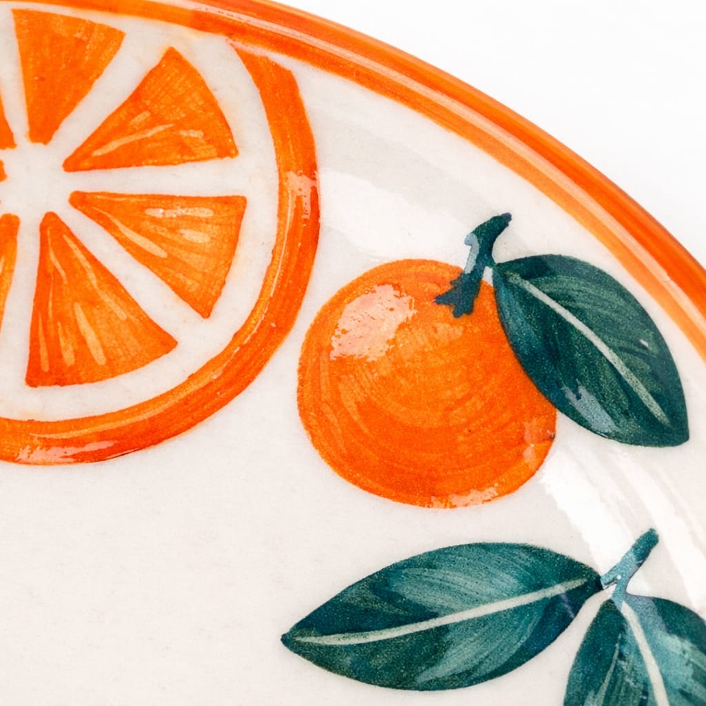 Decorative plate with orange slices and leaves on a white background