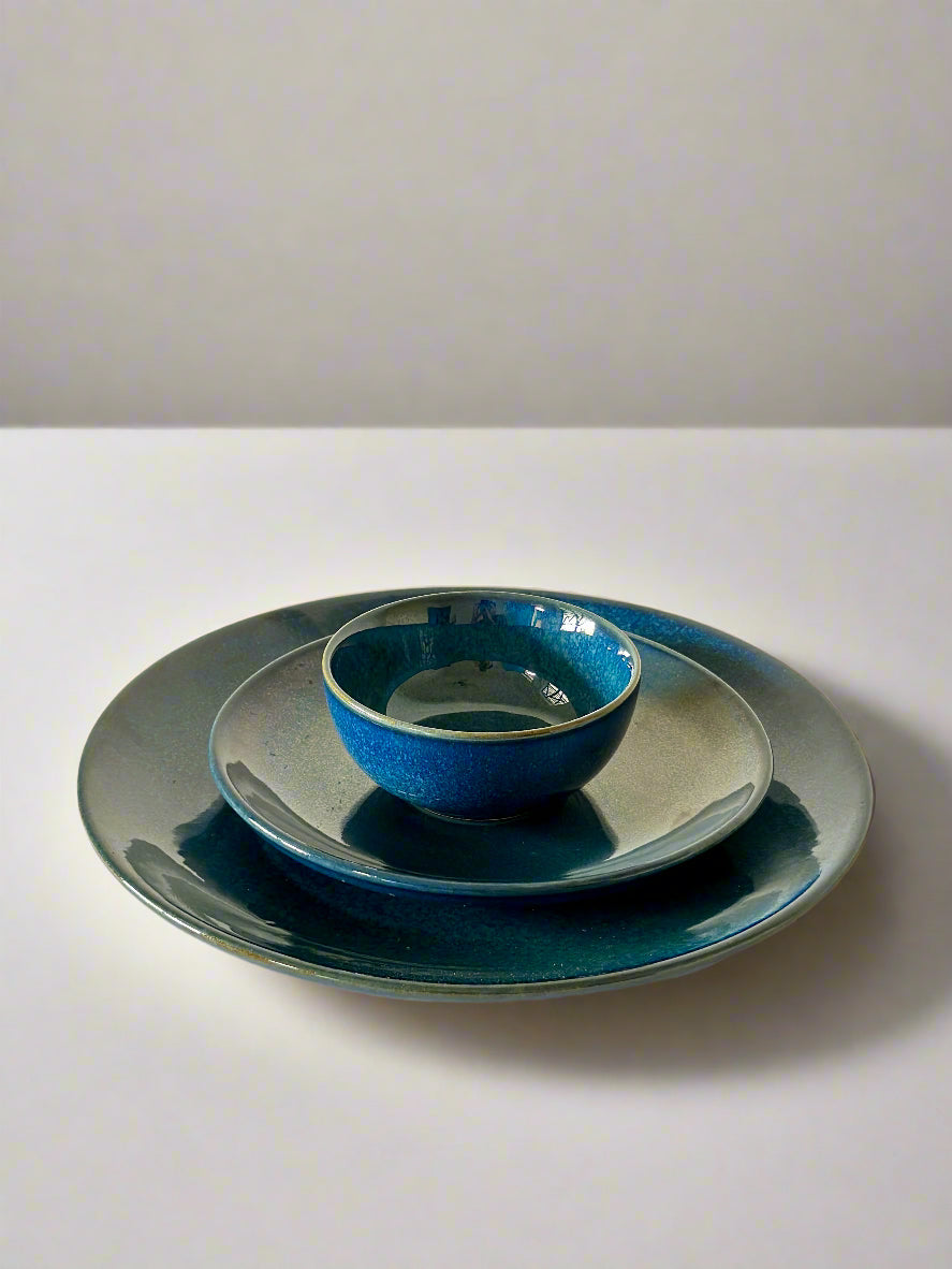 Set of blue ceramic plates on a white surface with a light beige wall background