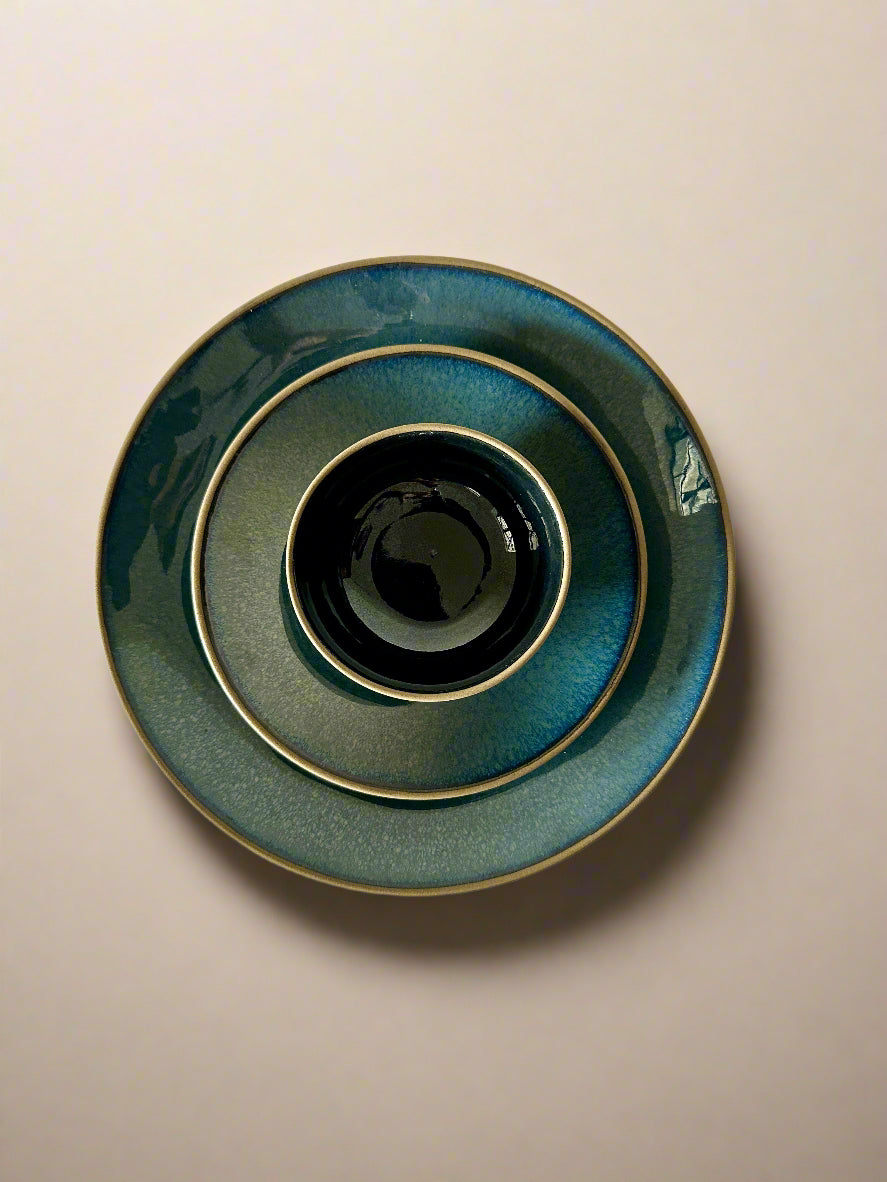 Set of three ceramic bowls in blue and black on a textured white surface