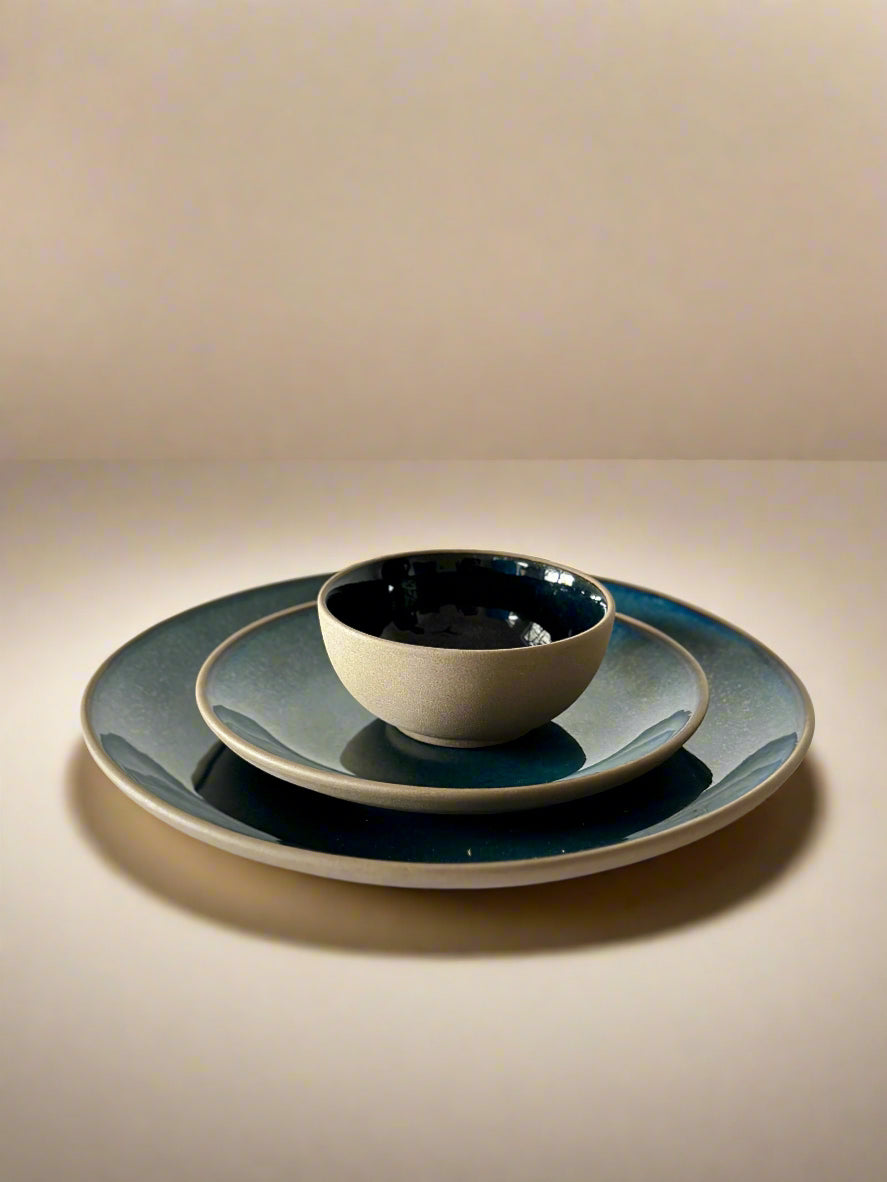 Set of ceramic plates and bowls on a white surface with a neutral background