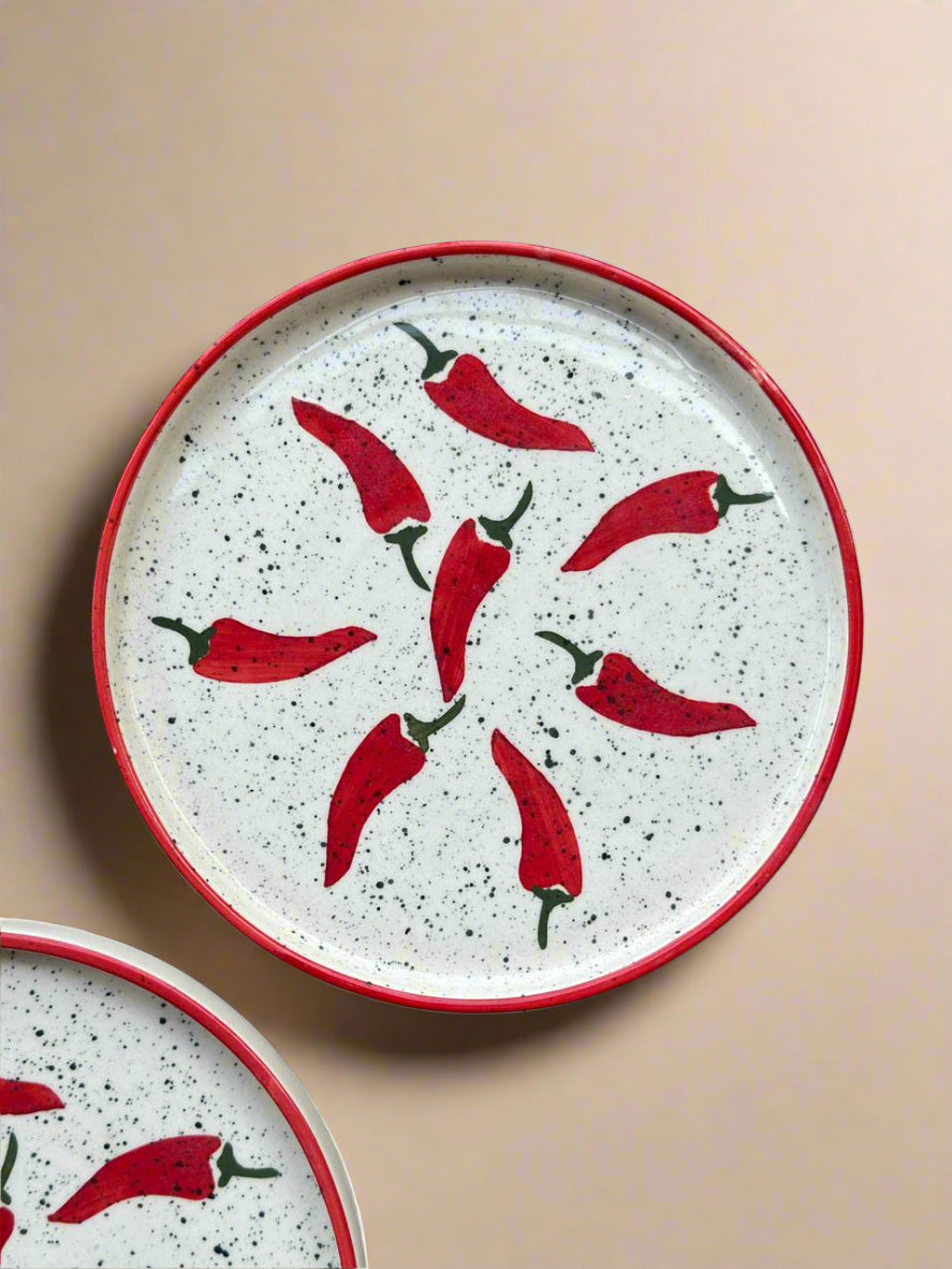 Speckled ceramic plate with red chili pepper design on a beige background