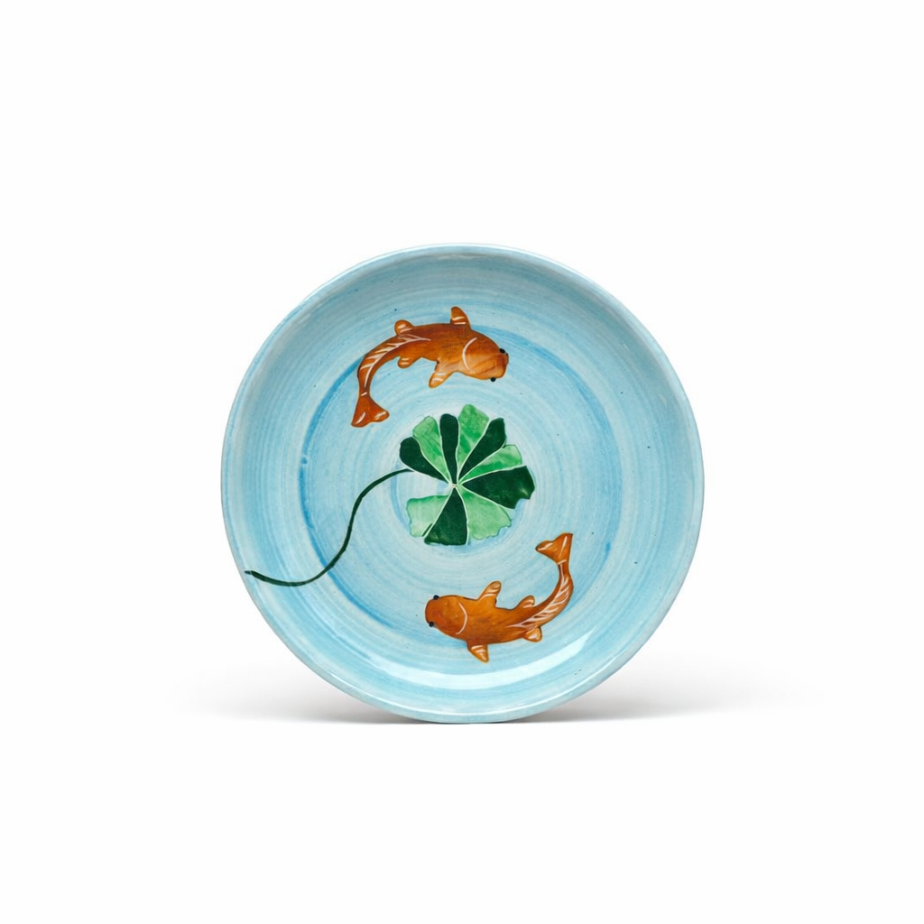 Decorative plate with koi fish and a clover on a light blue background