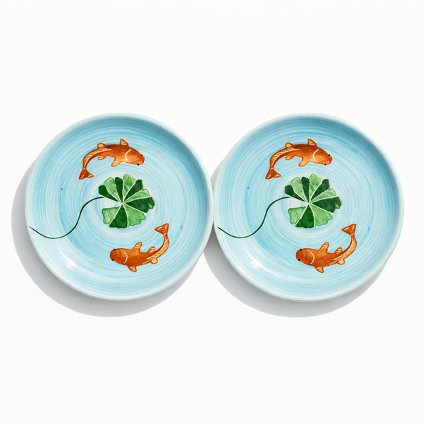 Two ceramic bowls with koi fish and clover design on a light blue background