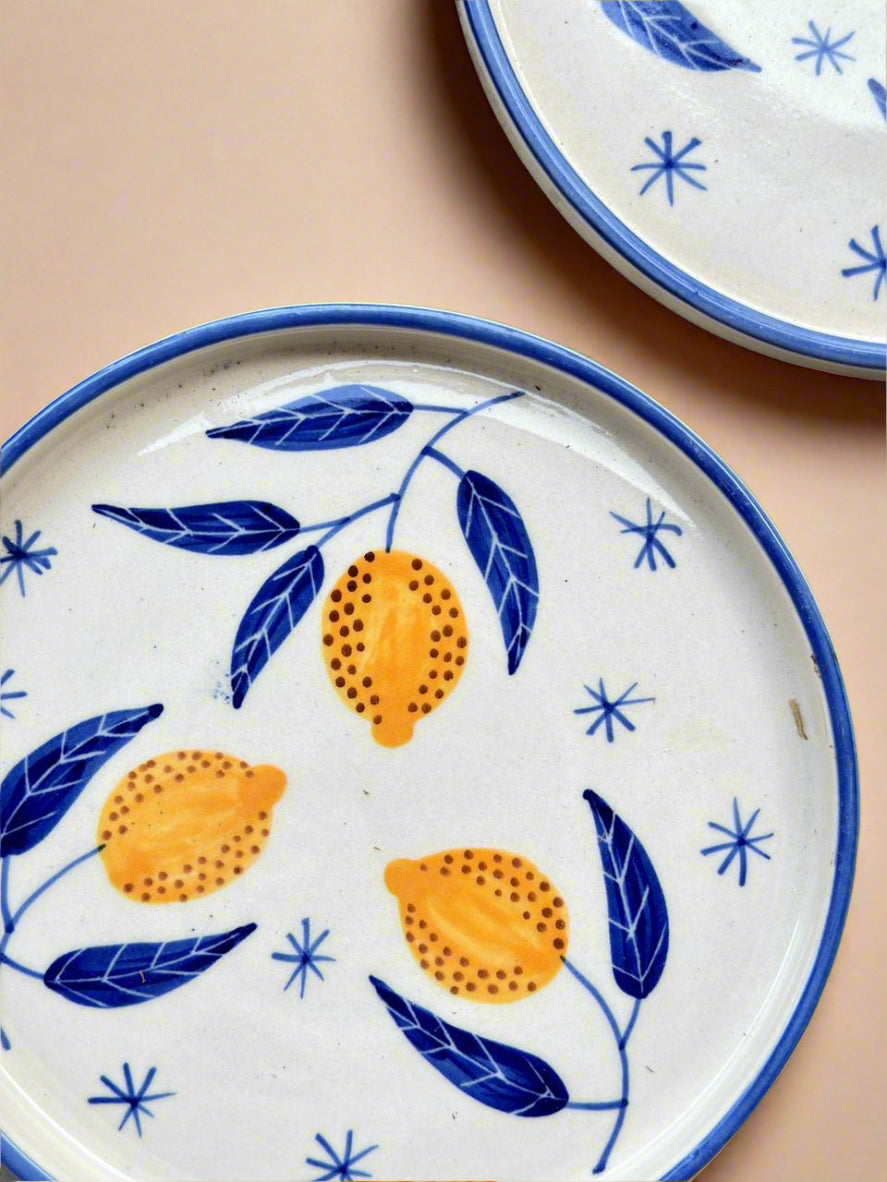 Ceramic plates with lemon and leaf design on a beige background