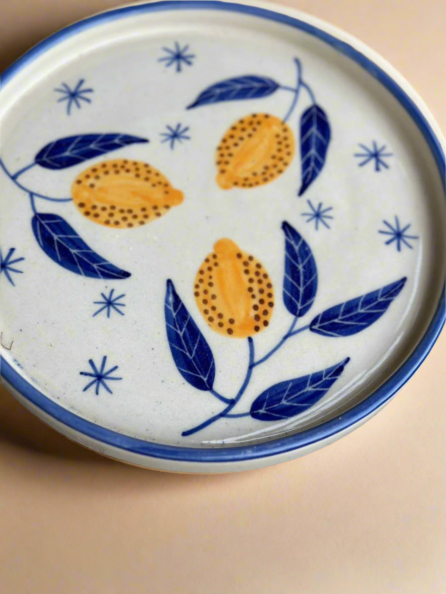 Ceramic plate with lemon and leaf design on a beige background