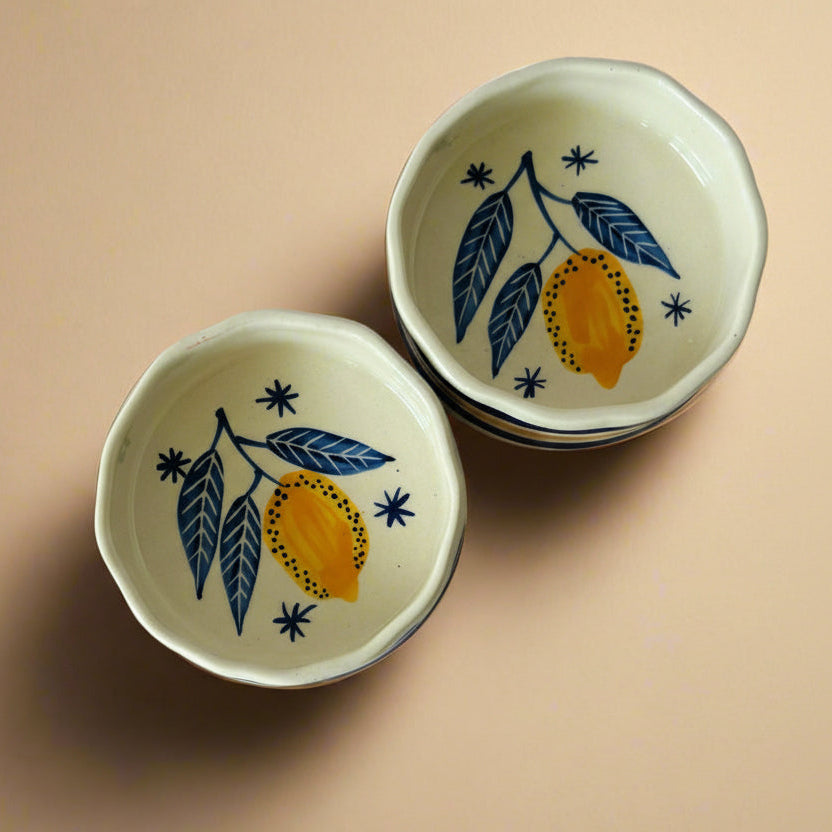 Two ceramic cereal bowls with a leaf and lemon pattern on a beige background.