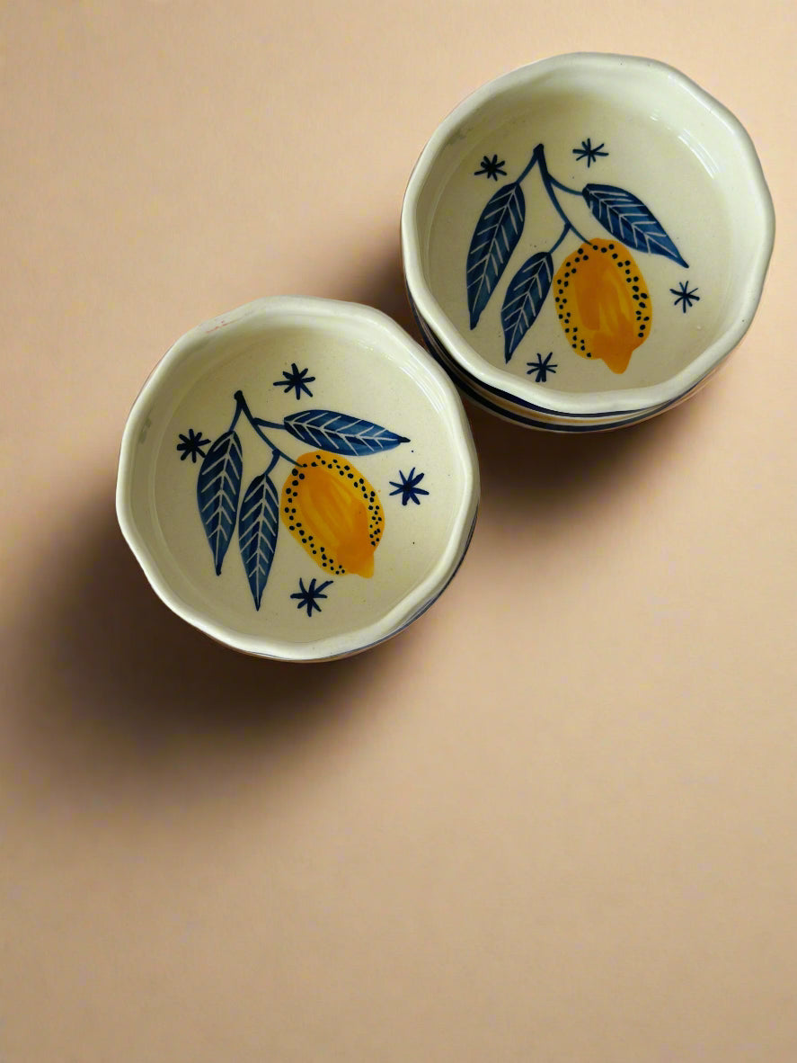 Two ceramic cereal bowls with a leaf and lemon pattern on a beige background.