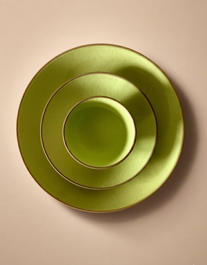 Set of three green ceramic plates stacked on a beige background
