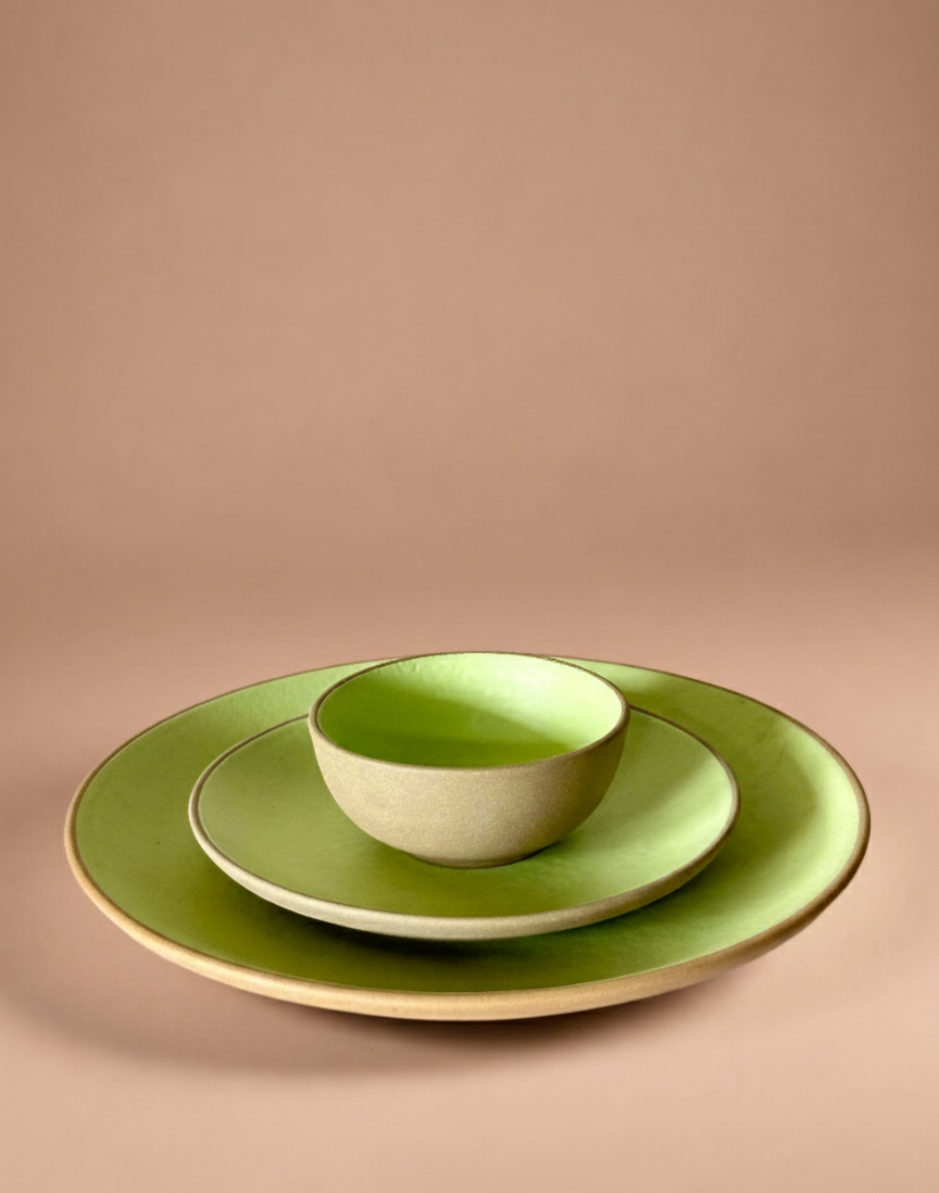 Set of green ceramic plates and bowl on a beige background