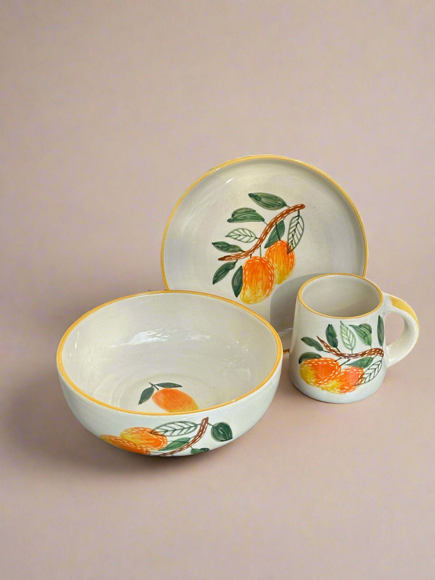 Ceramic dishes with orange and leaf design on a metallic surface