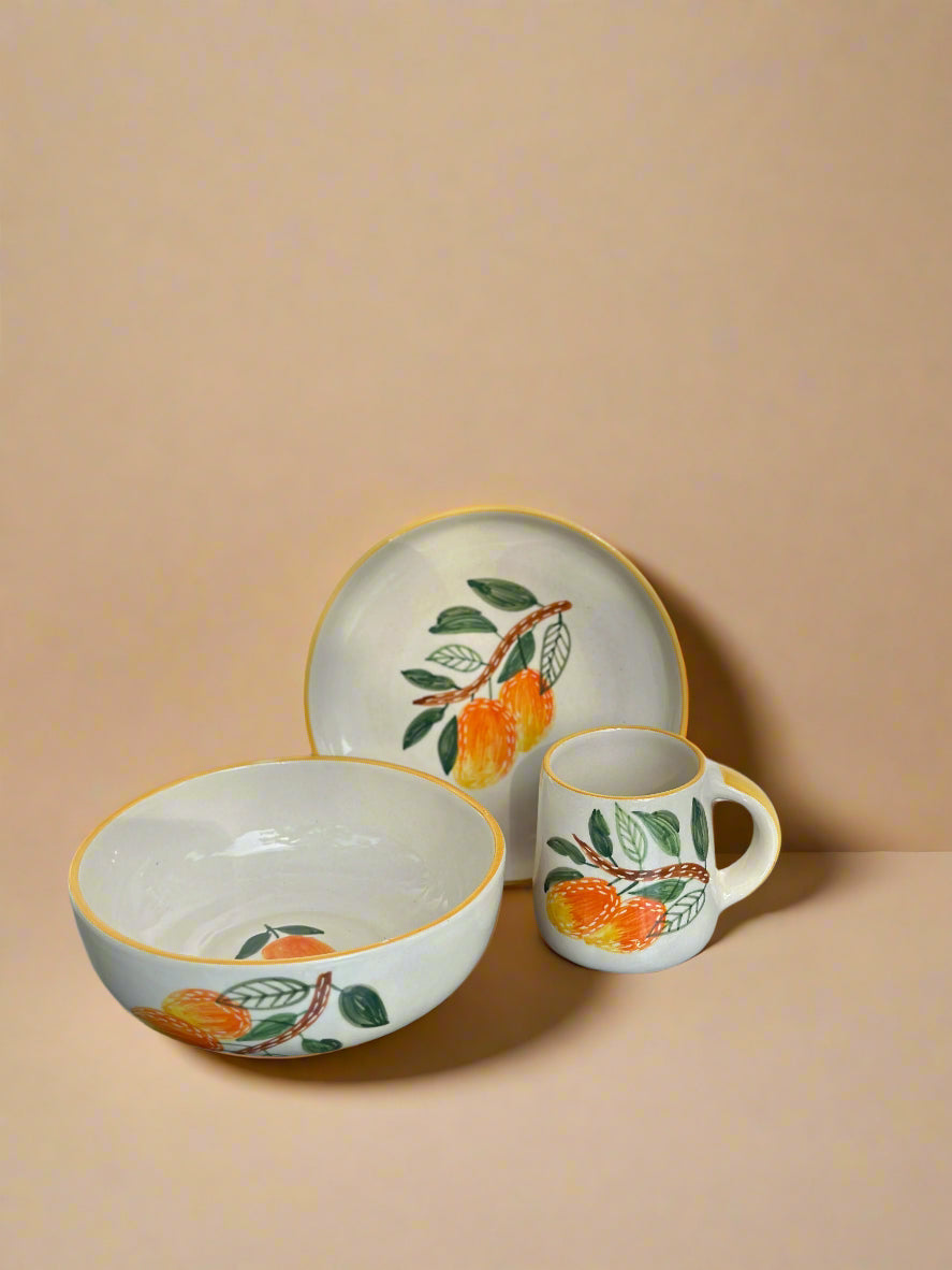 Ceramic set with bowl, plate, and mug featuring peach designs on a beige background