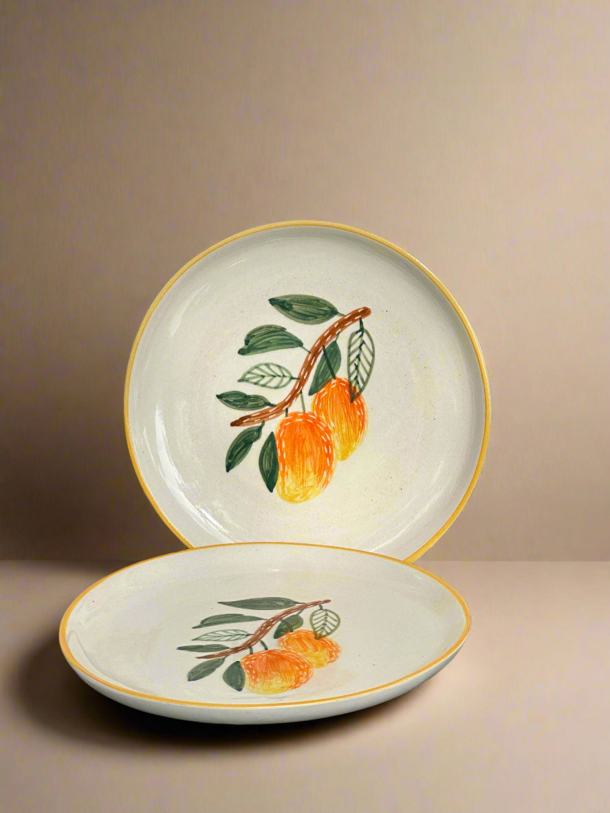 Two ceramic plates with fruit design on a gray surface