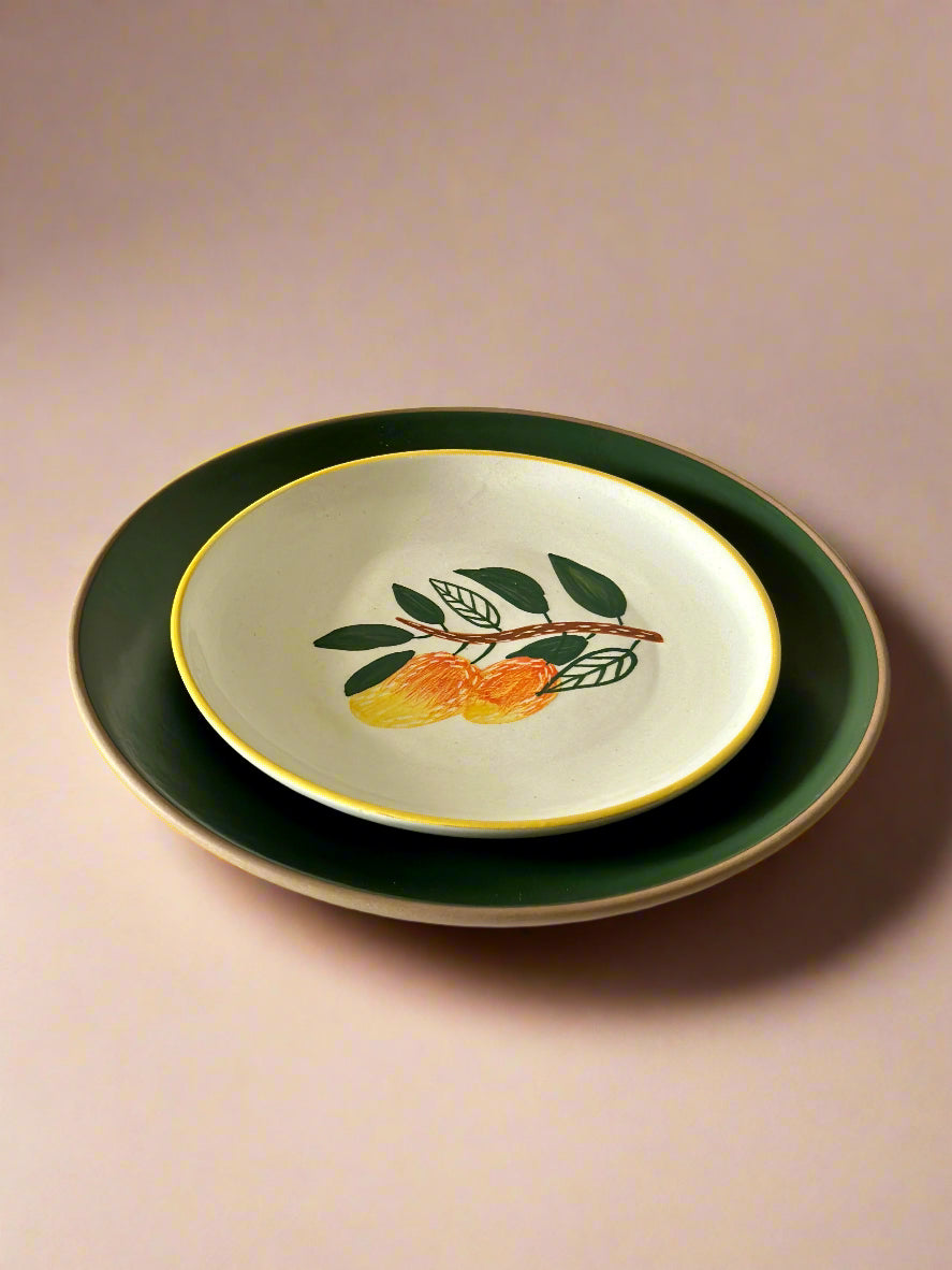 Decorative ceramic bowl with fruit design on a matching plate against a beige background