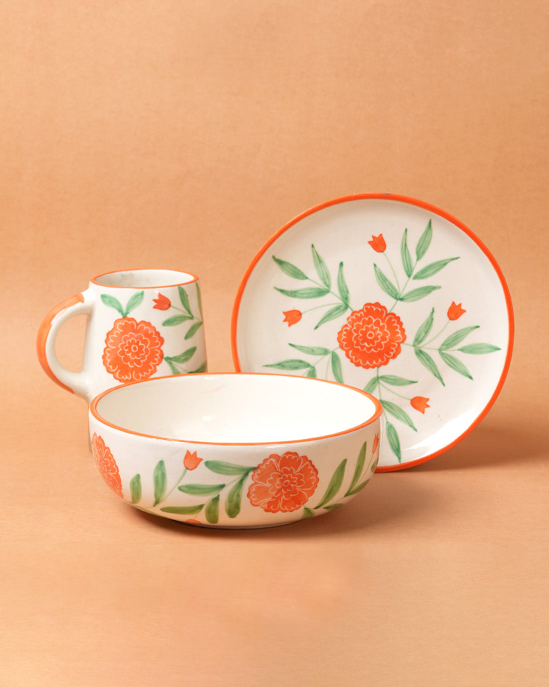 Ceramic bowl, mug, and plate set with floral design on a beige background