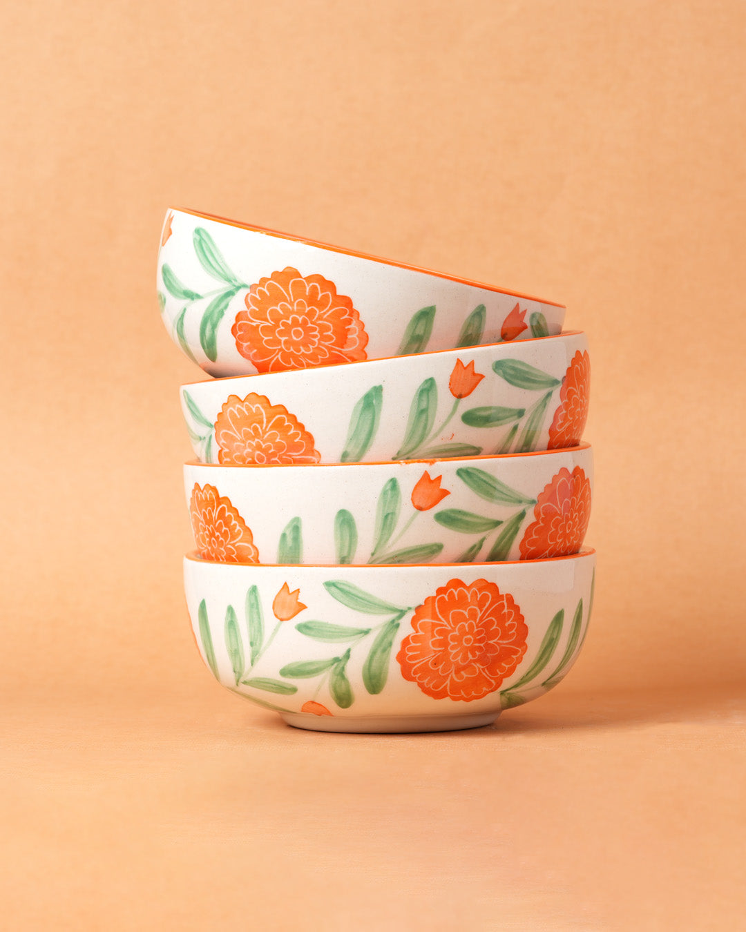 Stack of four ceramic bowls with floral pattern on a beige background
