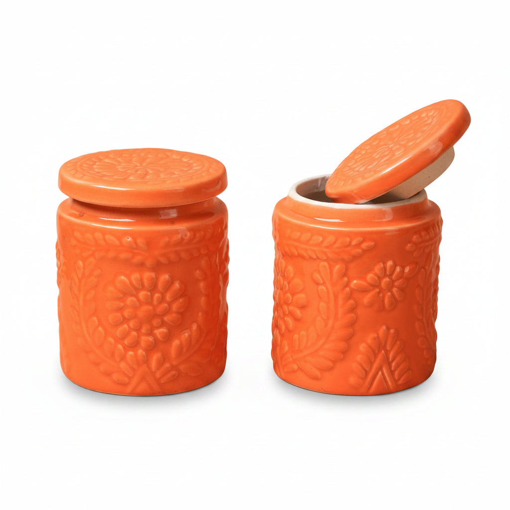 Two orange ceramic jars with embossed designs on a beige background