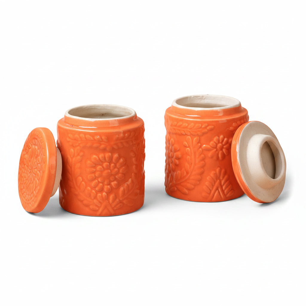Two orange ceramic jars with textured design on a beige background