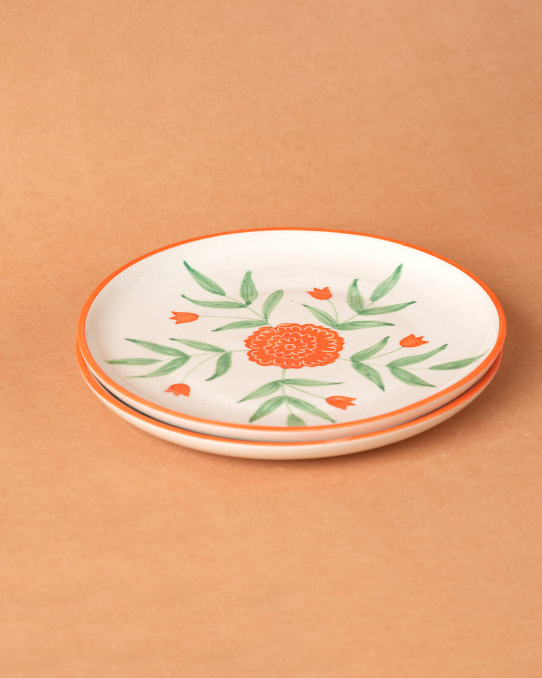 Stack of ceramic plates with floral design on a beige background