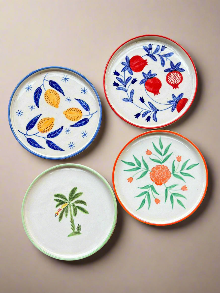 Four decorative plates with floral and botanical designs on a beige background