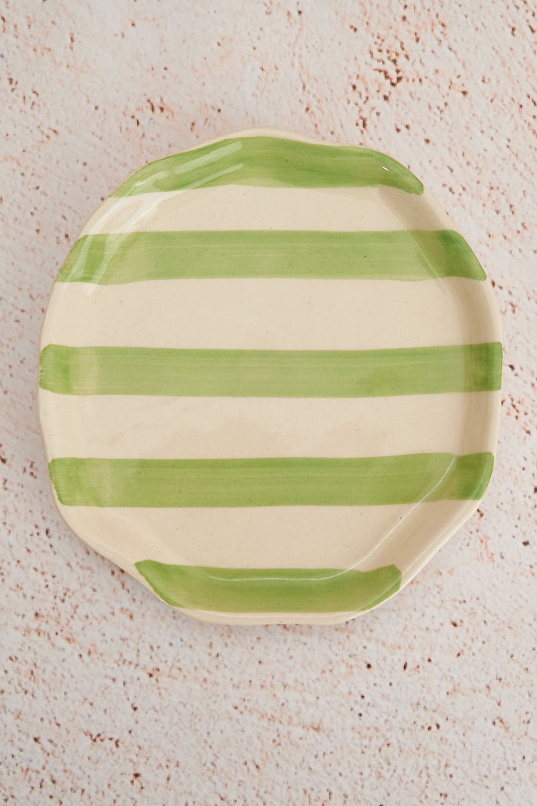 Green and white striped ceramic plate on a textured surface